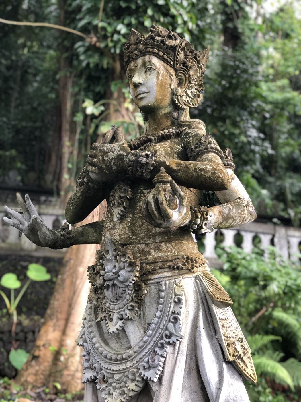 Carved temple guardian surrounded by tropical foliage