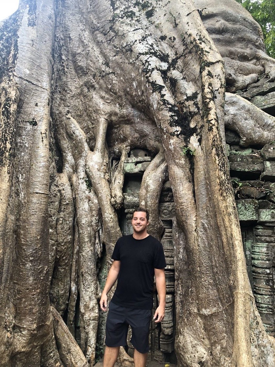 Mike standing among the giant tree roots at Ta Prohm