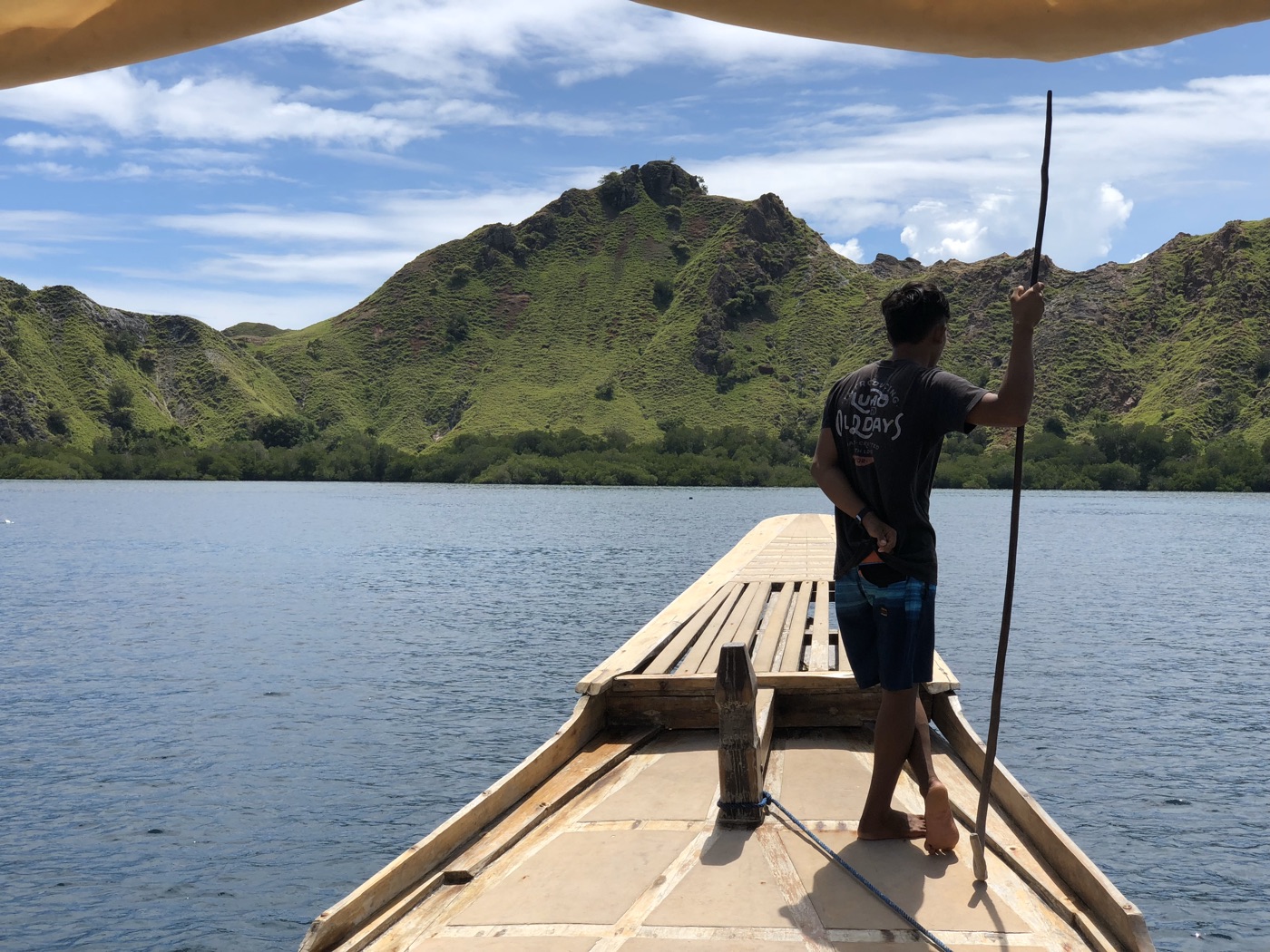 A wooden boat approaching the green islands of Komodo